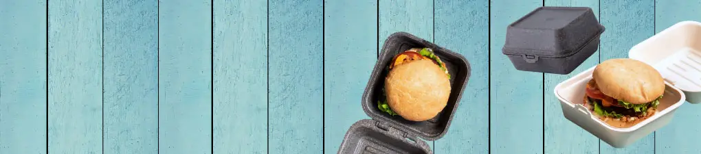 Grüner Cartoon-Chef mit einem Löffel neben einem Burger in einer braunen Takeout-Box auf blauem Holzuntergrund.