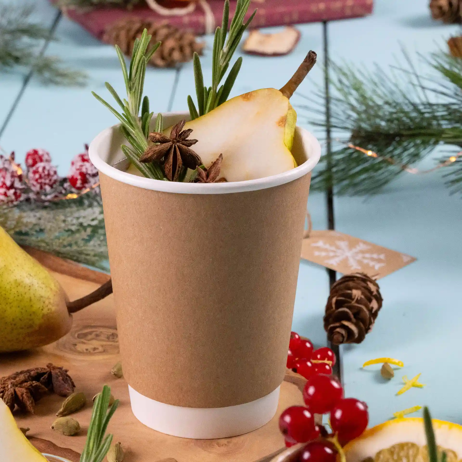 Brauner doppelwandiger Becher mit weißem Innenraum, gefüllt mit einer Scheibe Birne, Rosmarin und Sternanis.