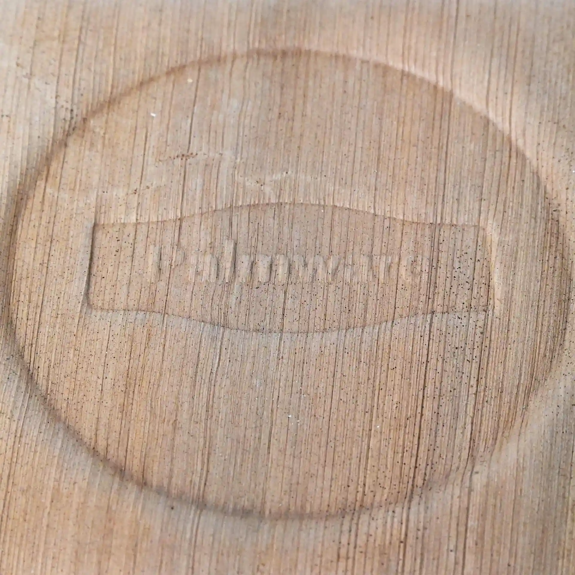Nahaufnahme einer hellen Holzoberfläche mit einem geprägten, kreisförmigen Design mit dem Text "Palmware®".