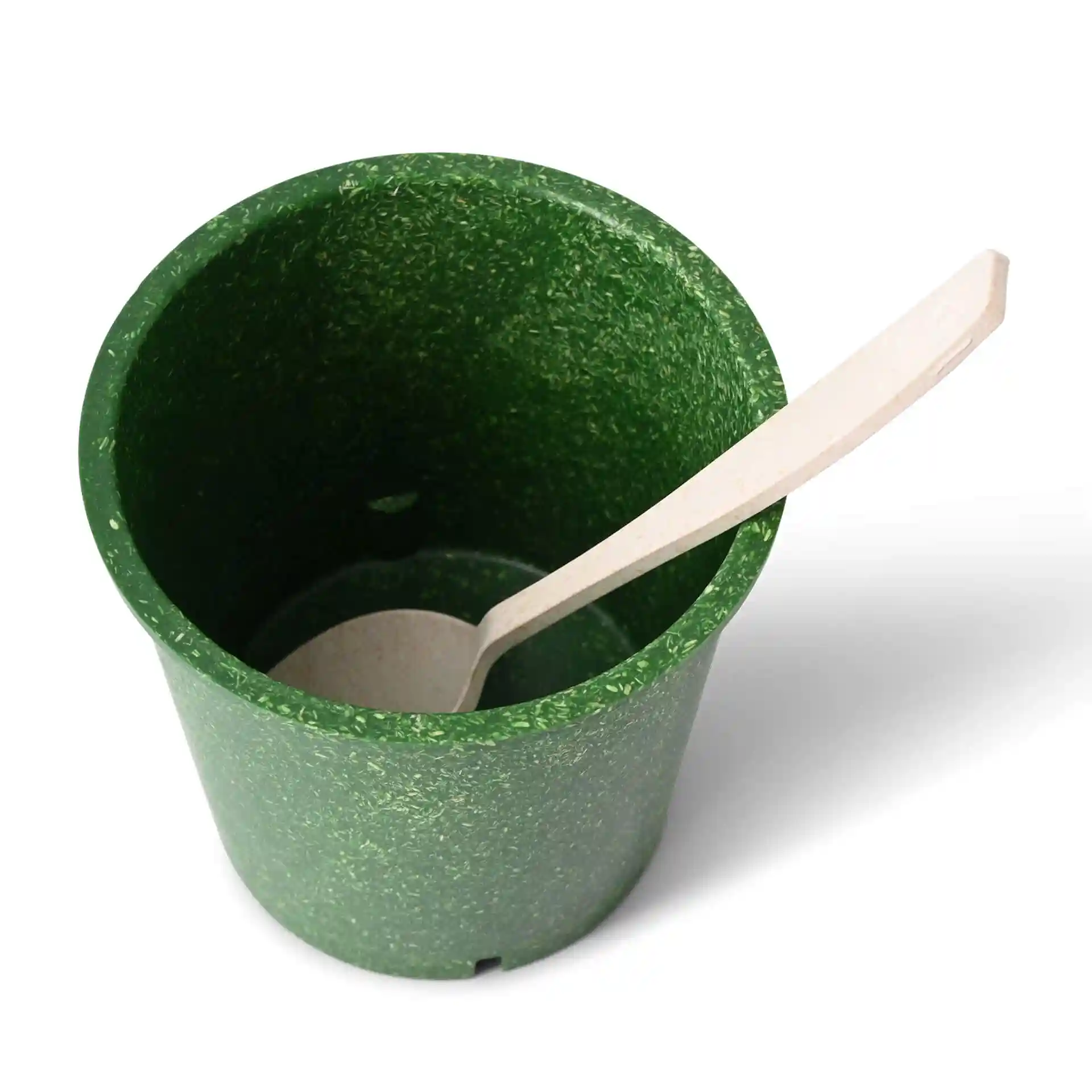 Green reusable cup made of bio compound with a round shape and a wooden spoon resting inside.