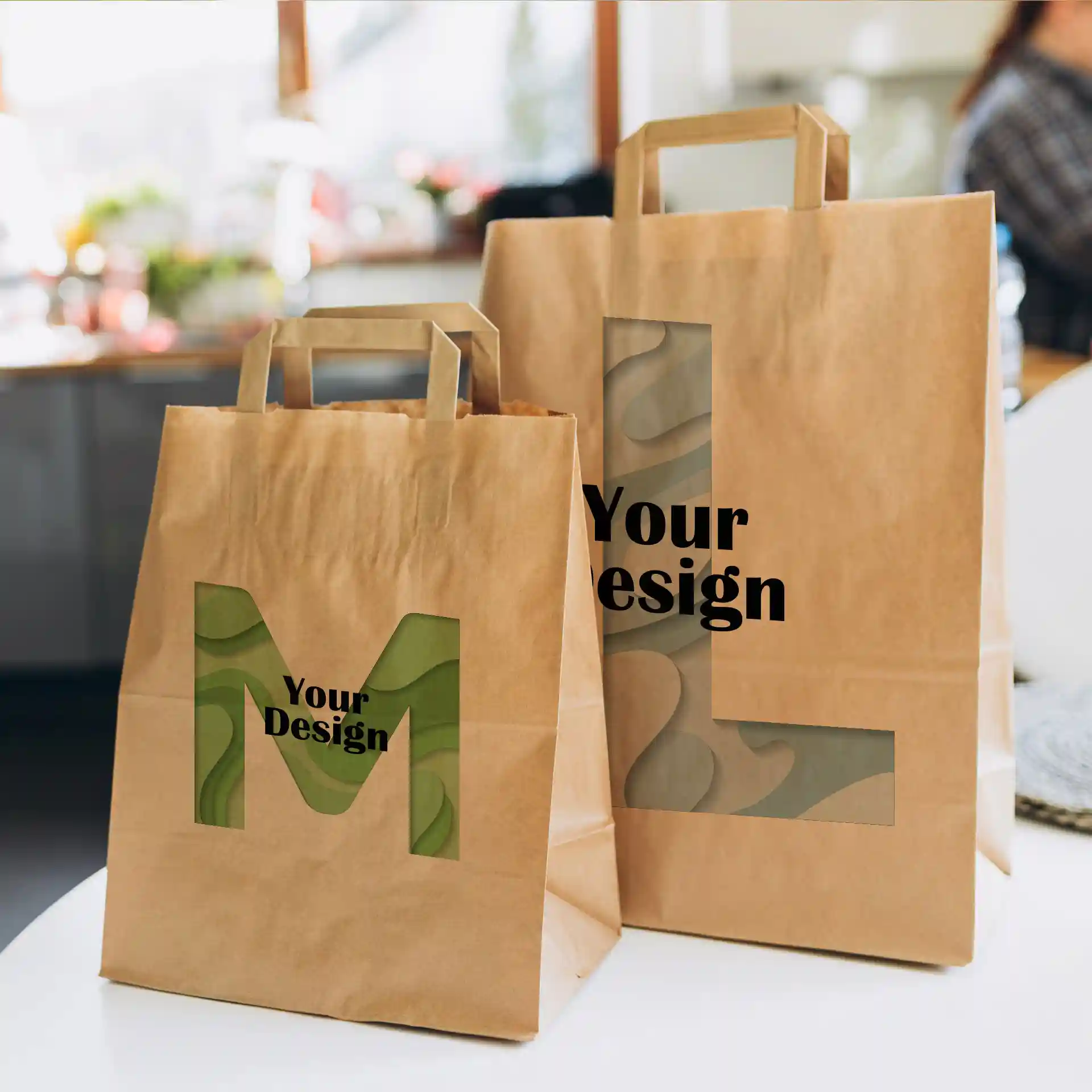 Brown paper carrier bags with cut-out designs, one labeled 'M' and the other 'L', on a table.