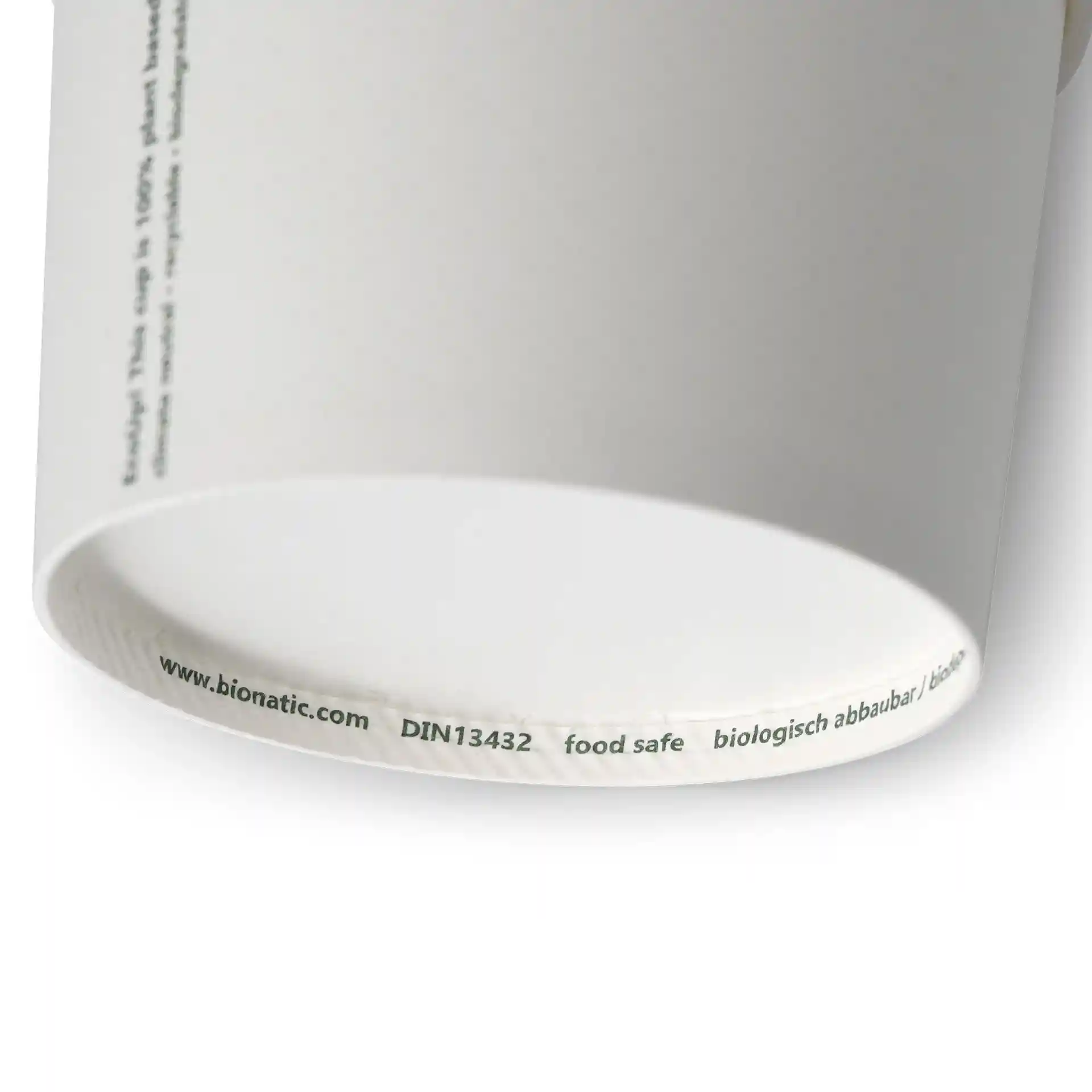 White cardboard soup cup with a round shape, showing the bottom edge and printed markings.