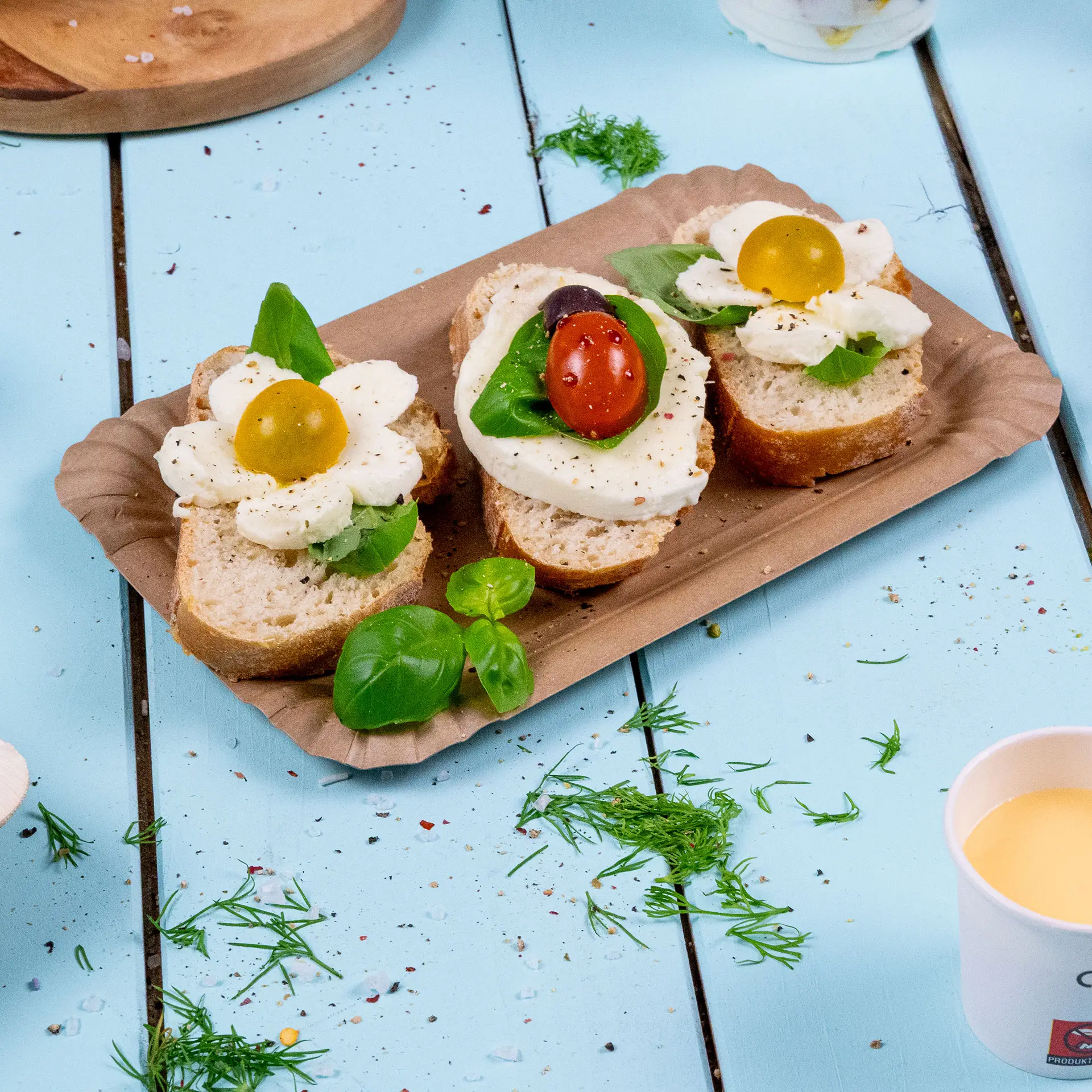 Ein rechteckiger brauner Pappteller hält zwei belegte Brote mit Mozzarella, Basilikum und Kirschtomaten.