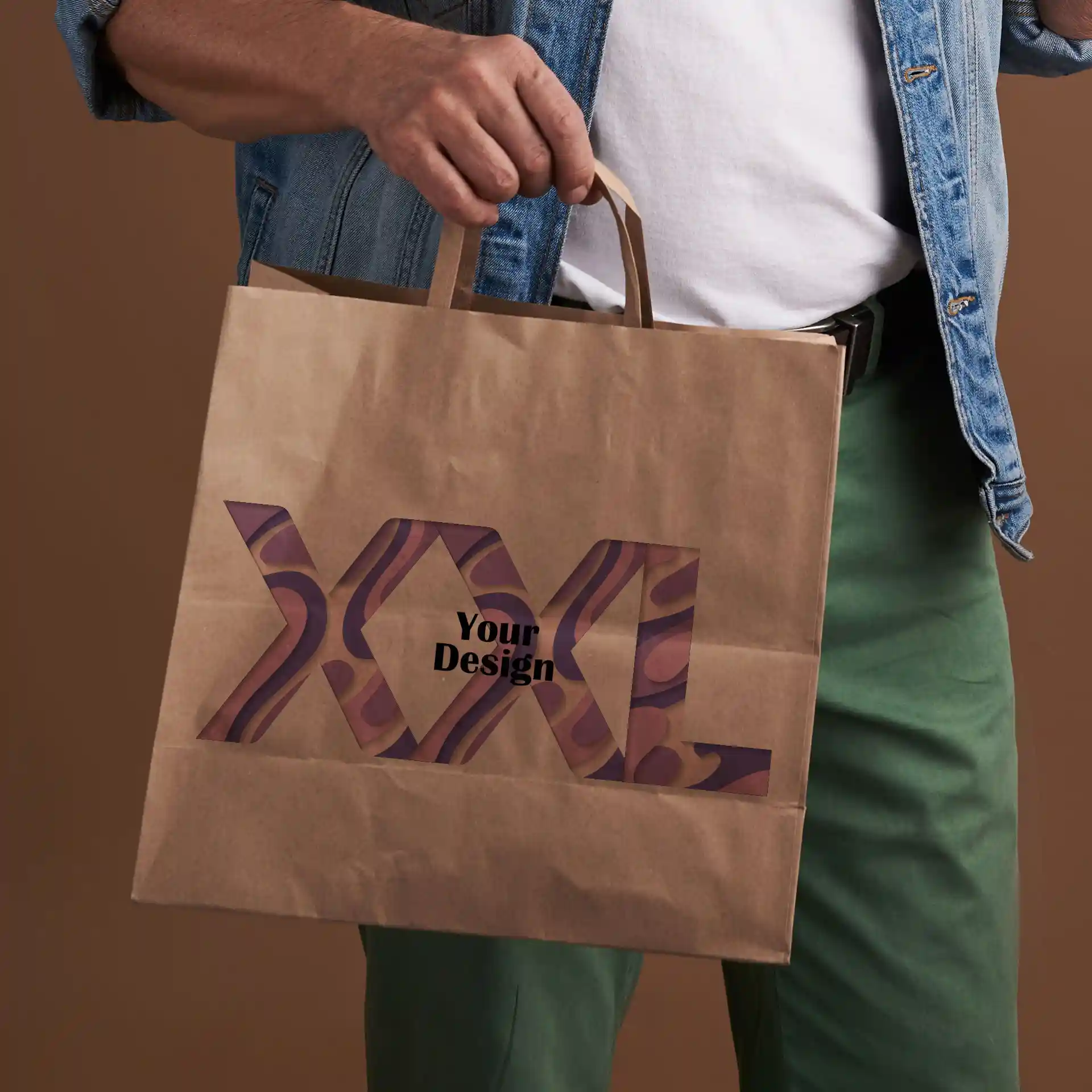 Brown paper carrier bag held by a person, featuring a cut-out design with the text "XXL Your Design".