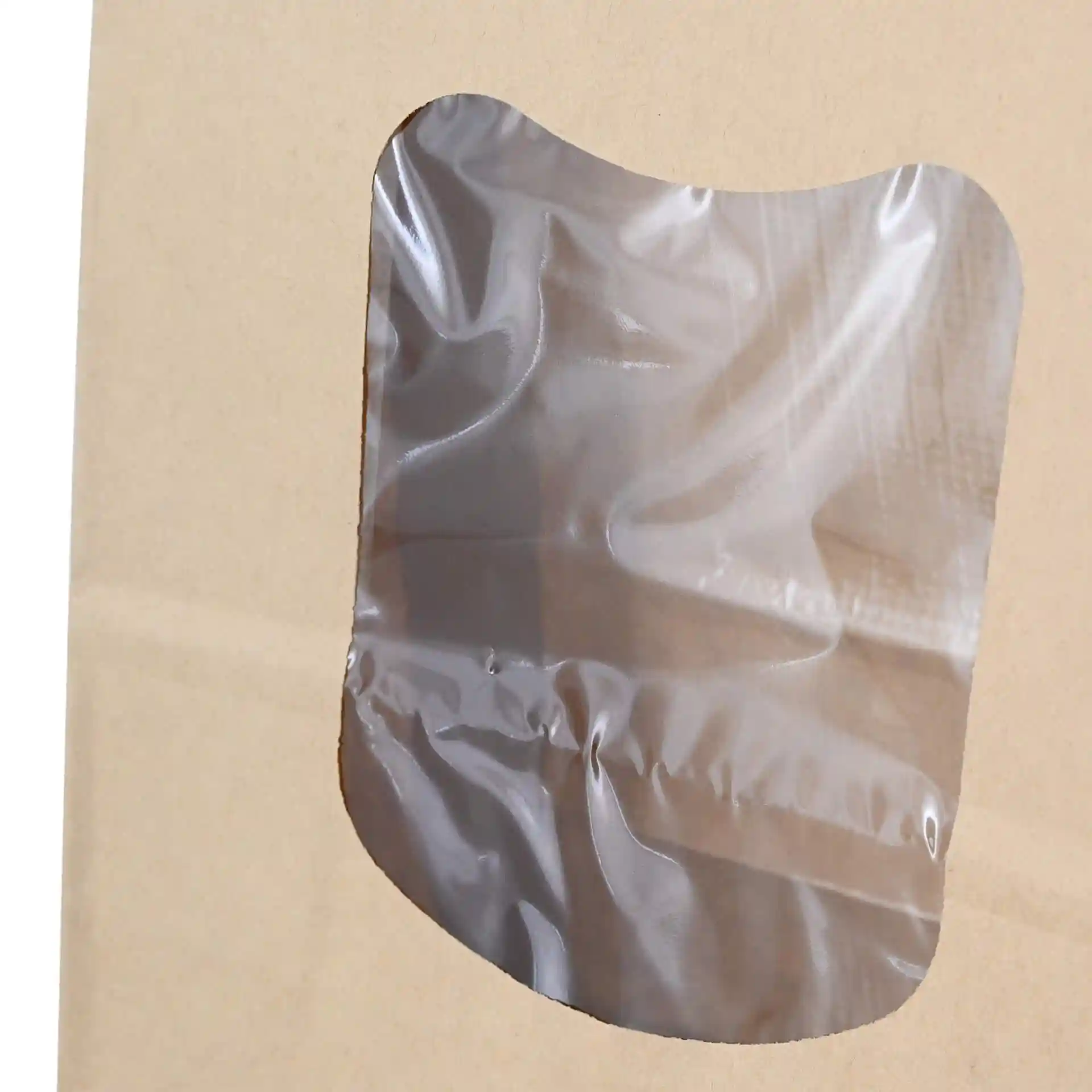 Close-up of a block bottom bag made of brown kraft paper with a transparent viewing window.