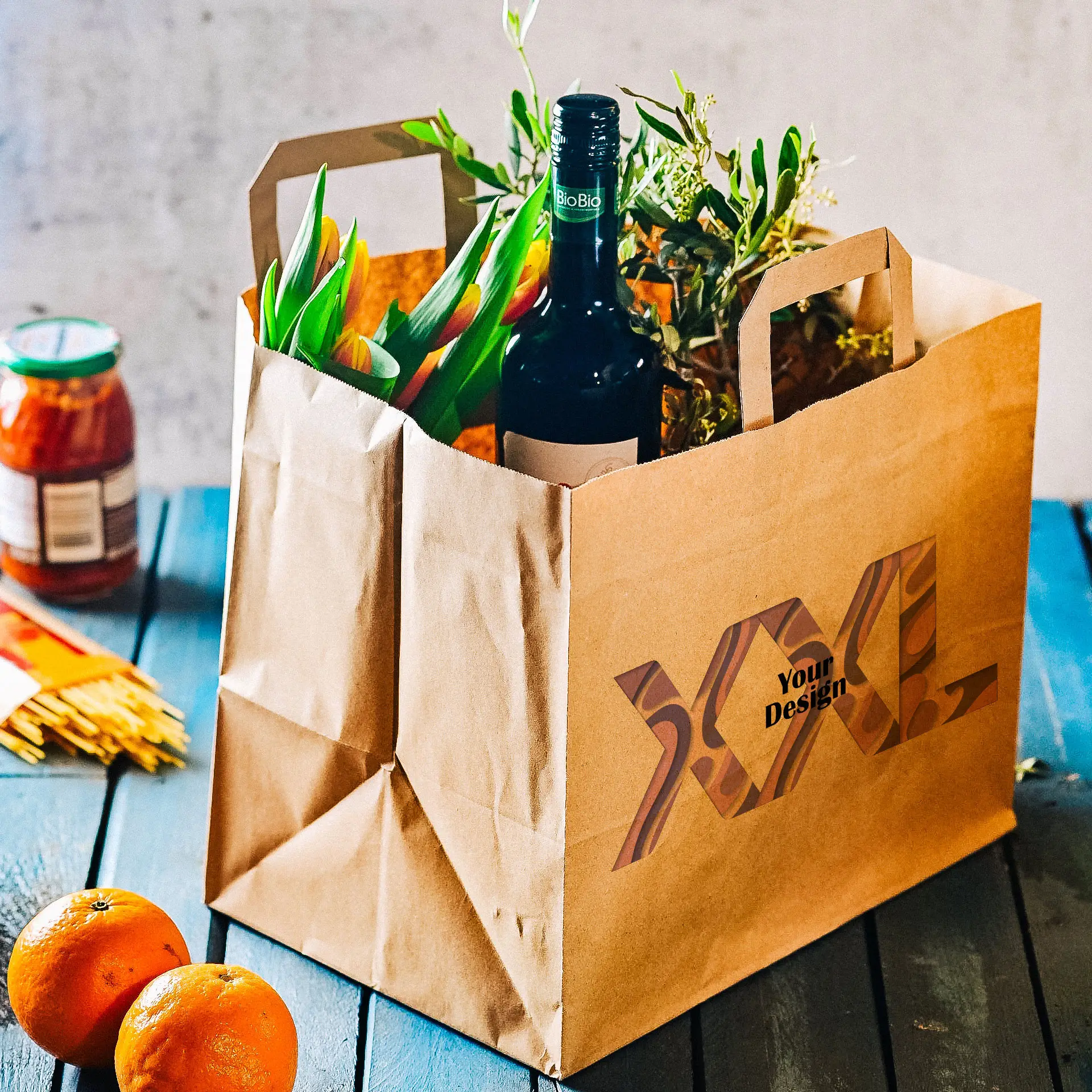 Customizable paper carrier bag made from recycled paper; contains flowers, a wine bottle, and oranges.