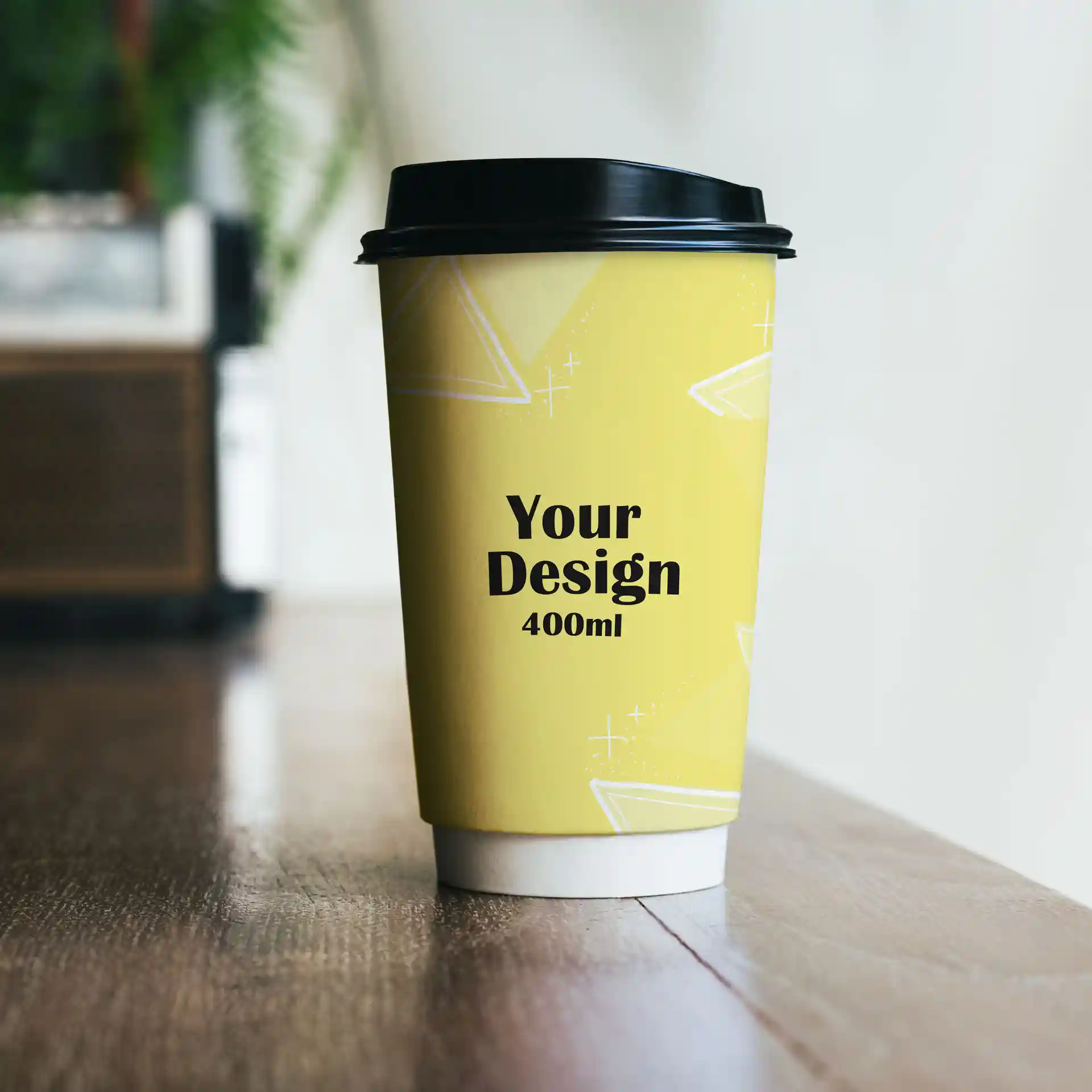 Gelber Becher mit schwarzem Deckel, mit Design und Text, der ein Volumen von 400 ml angibt.