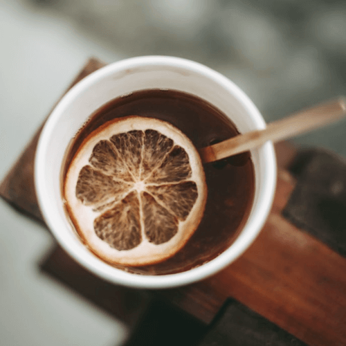 White single-wall paper cup with mulled wine orange and wood stirrer